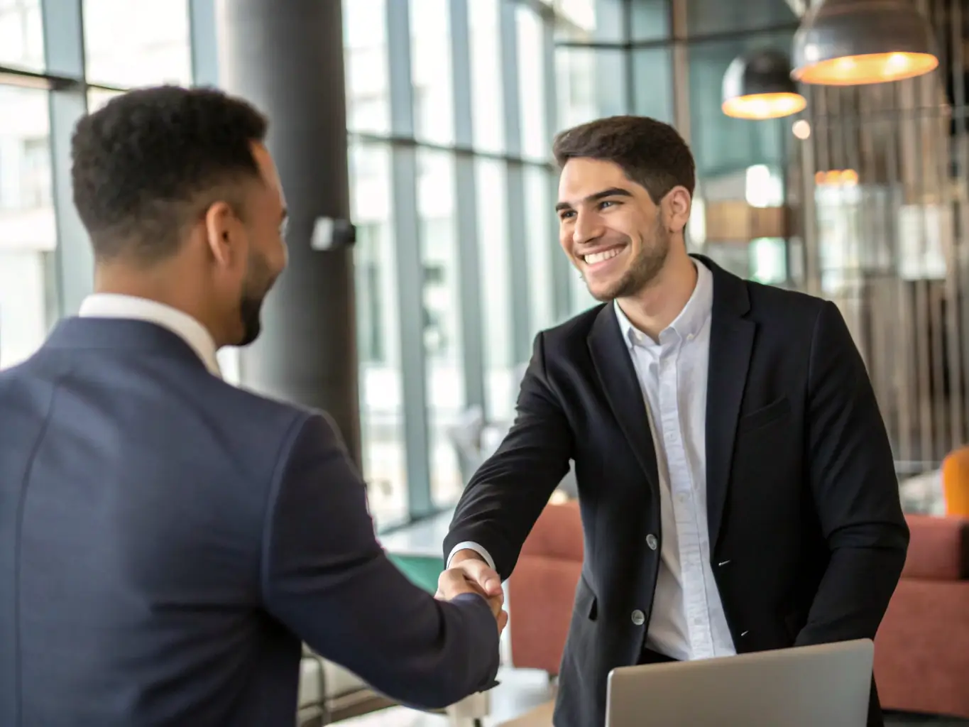 A professional candidate in a suit confidently shaking hands with a hiring manager in a modern office setting, symbolizing successful candidate placement by Asspire Recruitment Services.